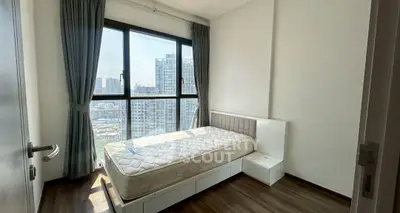 Bright bedroom with large window and city view, featuring a single bed and modern decor.
