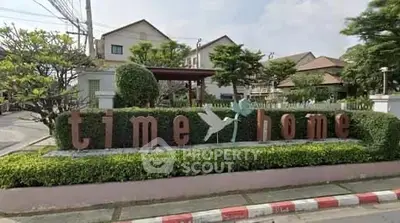 Charming residential community entrance with lush greenery and welcoming sign.