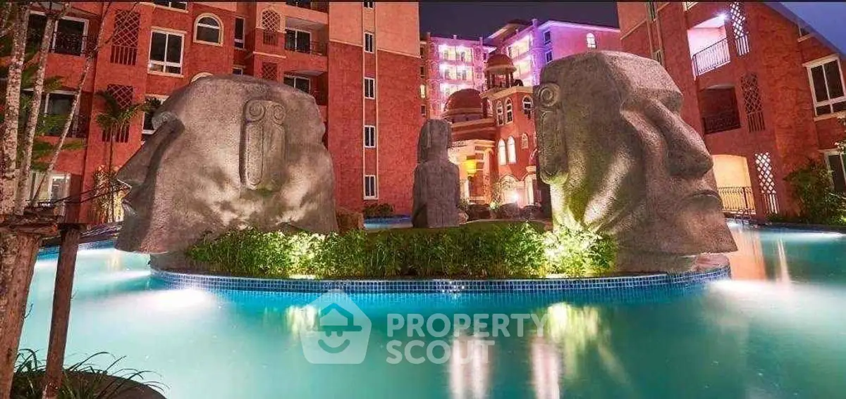 Stunning night view of a unique residential complex with illuminated pool and artistic stone sculptures.