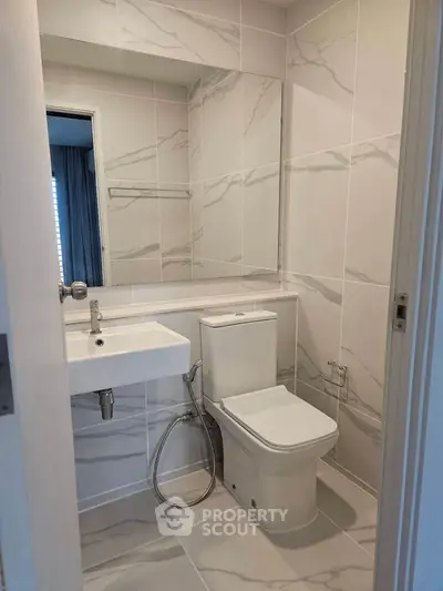 Modern bathroom with sleek white fixtures and marble-style tiles, perfect for a contemporary home.