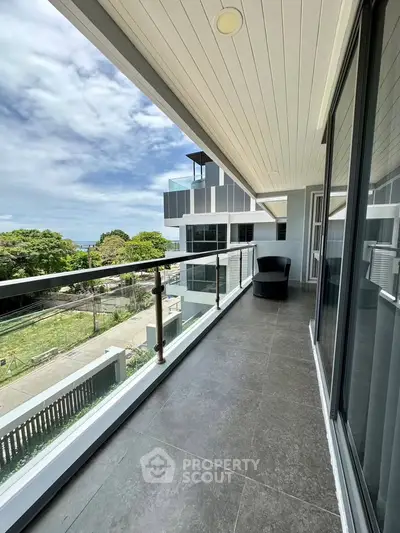 Spacious balcony with modern railing and scenic view in contemporary apartment building.
