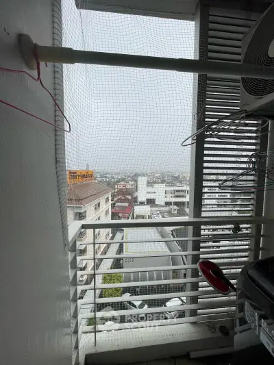 High-rise balcony with city view, featuring safety netting and clothes drying area.