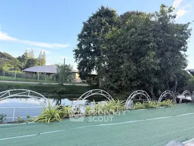 Charming outdoor garden area with lush greenery and serene water view, perfect for relaxation and leisure.