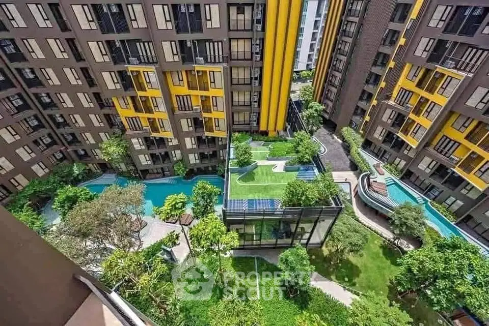 Stunning aerial view of modern apartment complex with lush gardens and swimming pool.