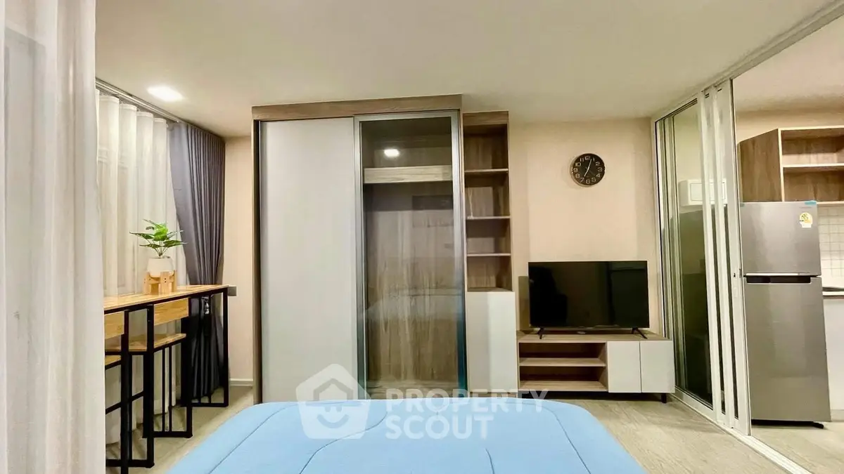 Modern bedroom with sliding wardrobe, TV, and dining area in open layout apartment.