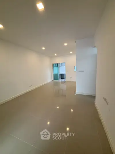 Spacious unfurnished room with glossy tiled flooring and recessed lighting