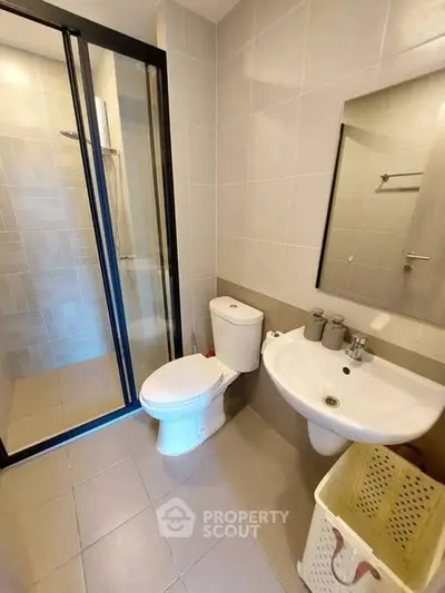 Modern bathroom with sleek design featuring a glass shower enclosure and contemporary fixtures.