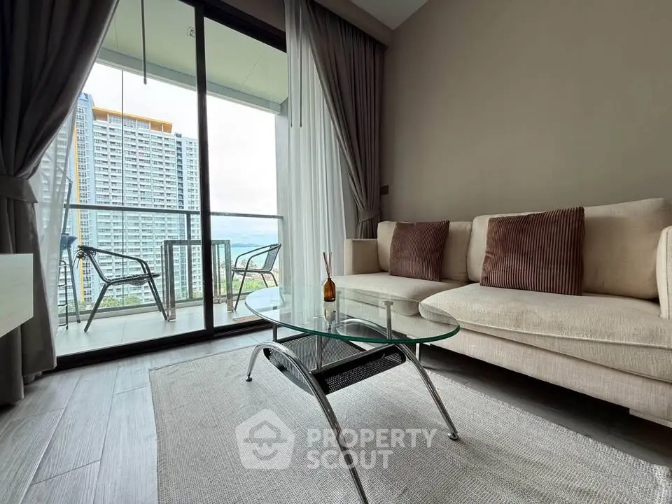 Modern living room with glass coffee table and balcony view in high-rise apartment