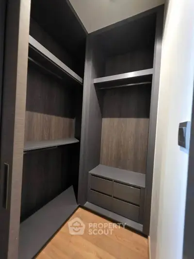 Spacious walk-in closet with modern dark wood finish and ample storage space.