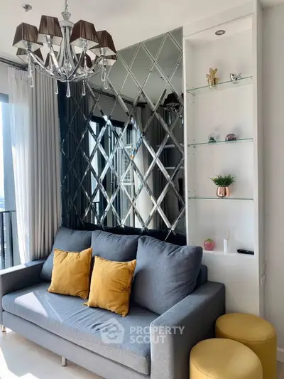 Modern living room with stylish chandelier and mirrored wall, featuring a cozy sofa and decorative shelves.