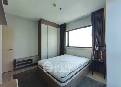 Modern bedroom with large window and stylish furnishings in a contemporary apartment.