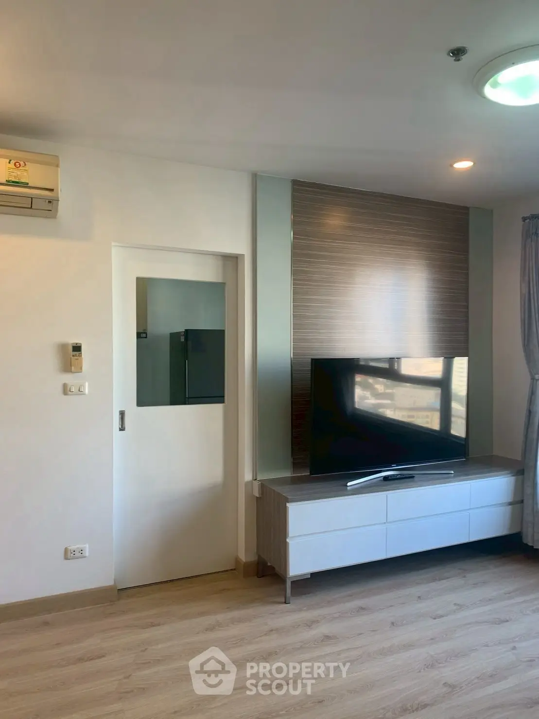 Modern living room with sleek TV setup and wooden flooring