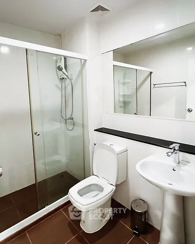 Modern bathroom with glass shower and sleek fixtures in contemporary apartment.