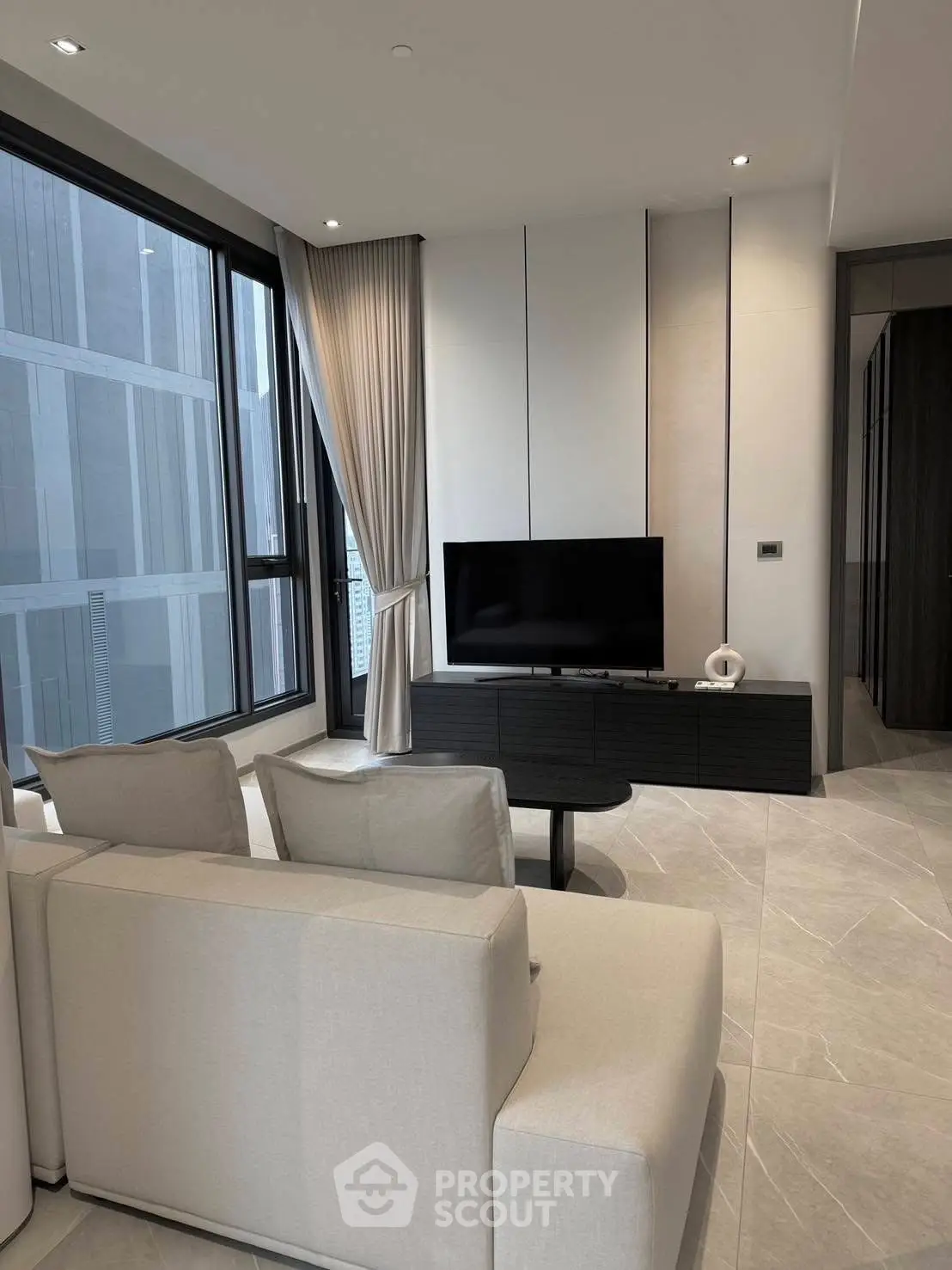 Modern living room with sleek design and large windows offering city views.