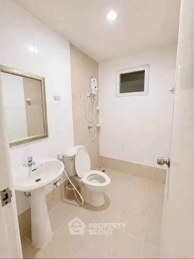 Modern bathroom with sleek fixtures and neutral tiles, featuring a shower and toilet.