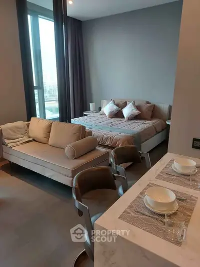 Modern studio apartment with stylish decor and city view, featuring a cozy bed and elegant dining area.