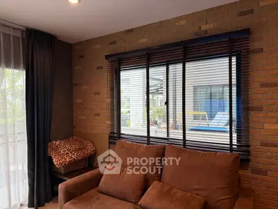 Cozy living room with brown sofa and large window overlooking outdoor area