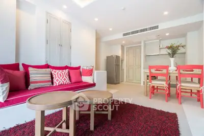 Charming living room with vibrant red accents and cozy seating, open to a modern kitchen area.