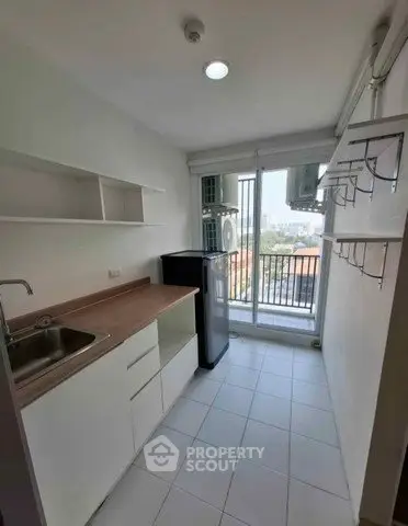 Compact kitchen with balcony view, featuring modern cabinetry and natural light.