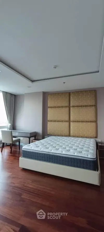 Spacious bedroom with modern decor and large windows offering natural light