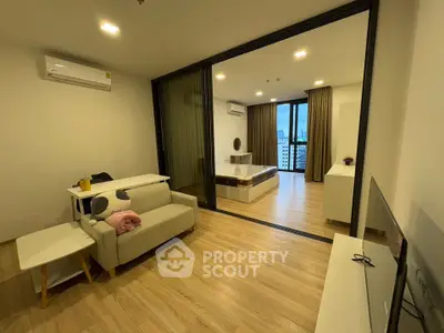 Modern open-plan living room with cozy sofa and spacious bedroom view
