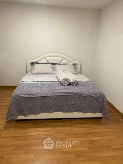 Spacious bedroom with elegant bed and wooden flooring, perfect for relaxation.