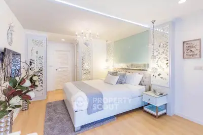 Luxurious bedroom with elegant decor, mirrored accents, and plush bedding in a modern apartment.