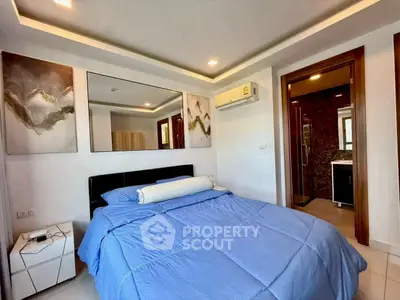 Modern bedroom with blue bedding, stylish decor, and ensuite bathroom in a contemporary apartment.