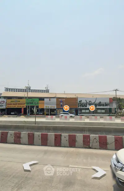 Commercial buildings along a busy highway with clear sky view.