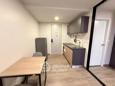Modern compact kitchen with sleek cabinetry and dining area in a cozy apartment.