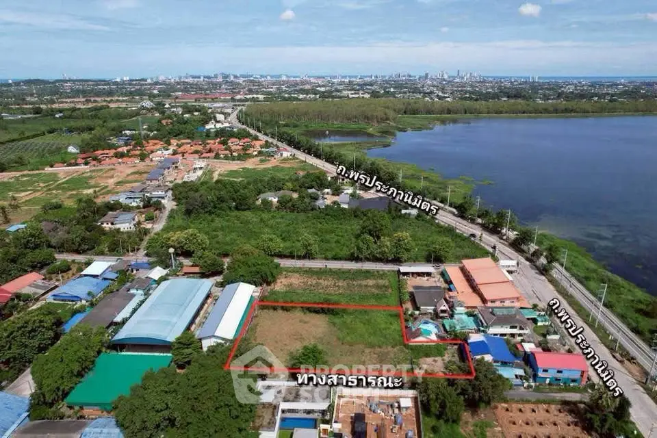 Aerial view of a prime real estate plot near a lake with city skyline in the background.
