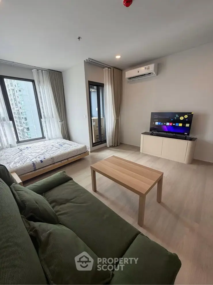 Modern living room with cozy sofa, TV, and large windows in a stylish apartment.