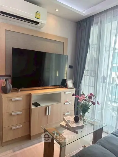 Modern living room with large TV and glass coffee table, perfect for relaxation.