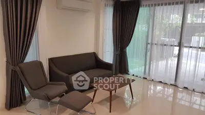 Modern living room with sleek furniture and large windows offering natural light.