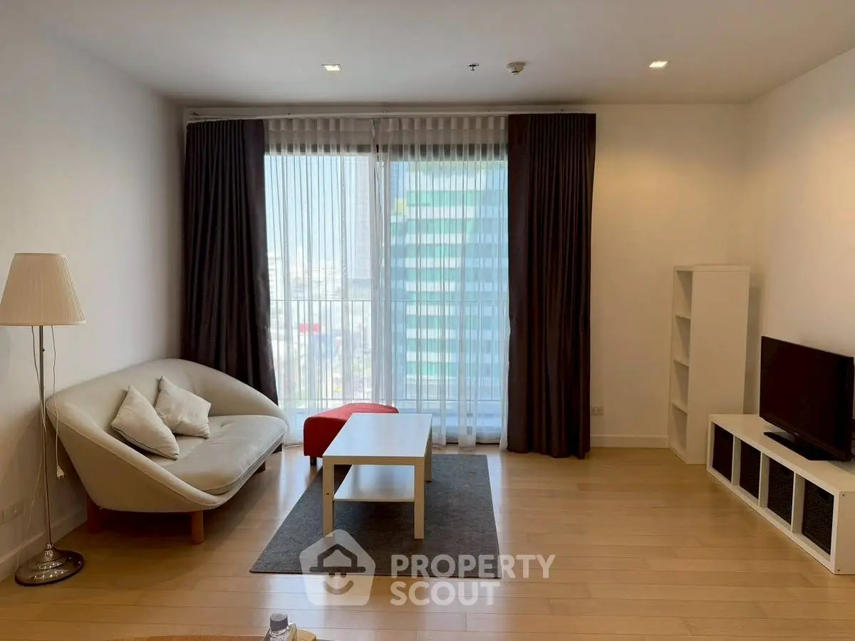 Modern living room with cozy sofa, TV, and large window view.