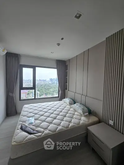 Modern bedroom with large window offering stunning city view and stylish decor.