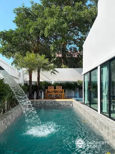 Luxurious private pool with waterfall feature and lush greenery in modern villa