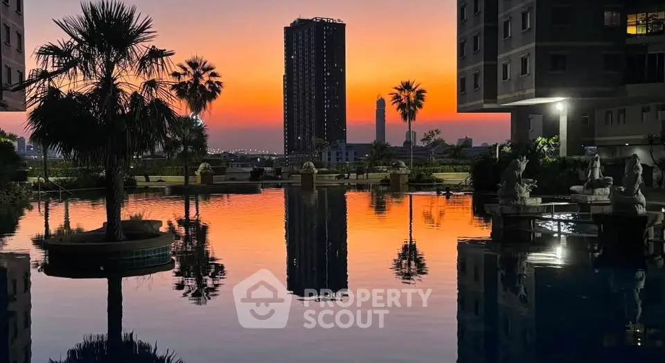 Stunning sunset view from a luxurious apartment complex with a serene pool and palm trees.