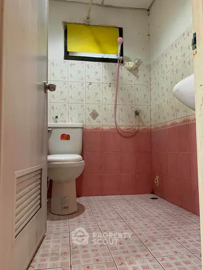 Cozy bathroom with pink tiles and compact layout, perfect for small spaces.