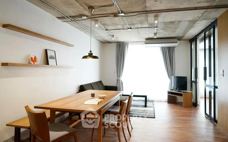 Modern living room with industrial ceiling, wooden dining table, and natural light.
