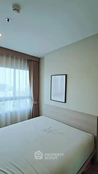 Cozy bedroom with large window and modern decor in a bright apartment.