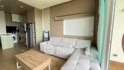 Modern living room with sleek kitchen, featuring a cozy sectional sofa and wooden accents.