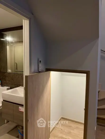 Unique bathroom with hidden storage under stairs, modern sink, and sleek design.