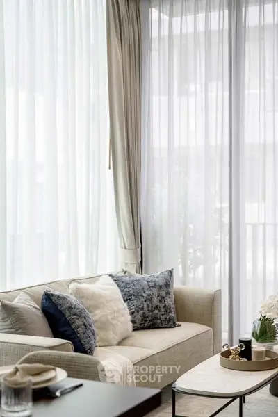 Elegant living room with plush sofa and stylish decor, featuring floor-to-ceiling windows for abundant natural light.