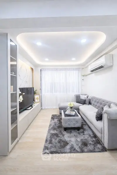 Elegant living room with modern decor, plush gray sofa, stylish lighting, and sleek entertainment unit.