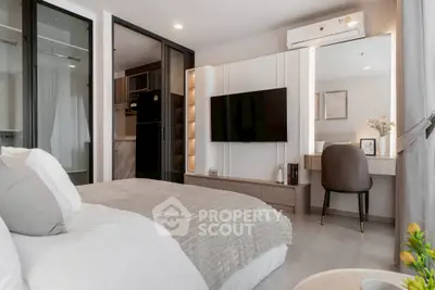 Modern bedroom with stylish decor, wall-mounted TV, and cozy workspace.