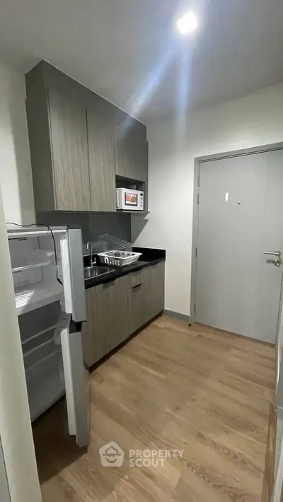 Modern kitchen with open fridge and microwave in compact apartment