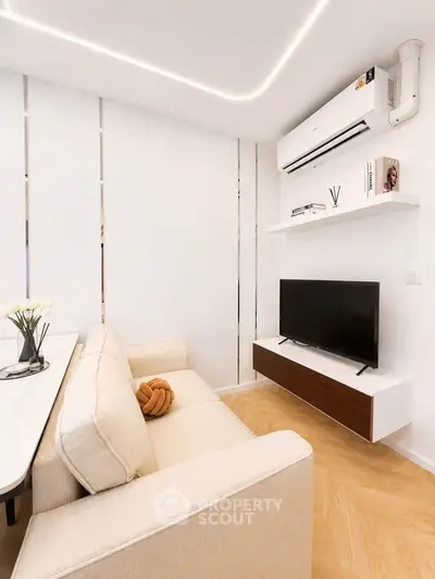 Modern living room with sleek design, featuring a beige sofa, wall-mounted TV, and air conditioning.