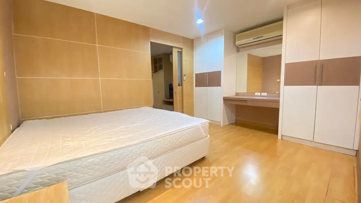 Spacious bedroom with modern design, featuring built-in wardrobe and wooden flooring.