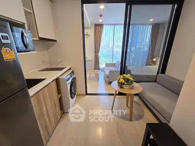 Modern studio apartment with open kitchen and cozy living area, featuring a washing machine and stylish decor.